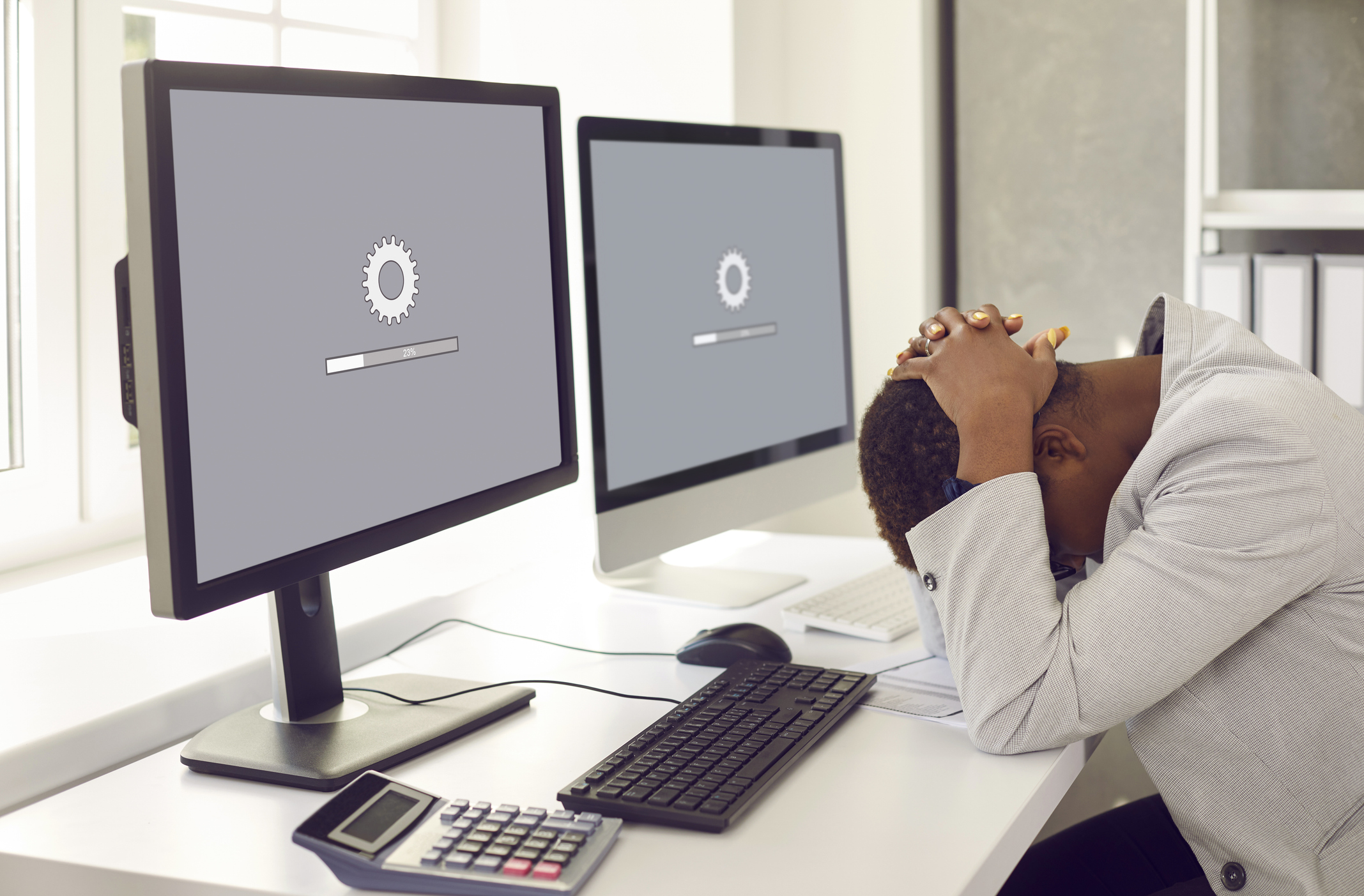 Woman sitting in front of office computers and waiting for software update to install